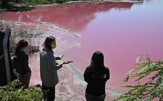 Locals gather at the shore of the Cerro Lake, formed from a meander of the Paraguay River, to protest against a nearby tannery which allegedly throws chemical disposals into the lake causing its water to turn pinkish red, in Limpio, 25 km northeast of Asuncion, on August 22, 2020. - According to experts from the National University Multidisciplinary Lab, the colour of the water is due to the presence of heavy metals like iron, chromium, and zinc, among others, commonly used in the tanning process. (Photo by Norberto DUARTE / AFP) (Photo by NORBERTO DUARTE/AFP via Getty Images)
