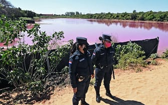 Police officers provide security to locals protesting on the shore of the Cerro Lake, formed from a meander of the Paraguay River, against a nearby tannery which allegedly throws chemical disposals into the lake causing its water to turn pinkish red, in Limpio, 25 km northeast of Asuncion, on August 22, 2020. - According to experts from the National University Multidisciplinary Lab, the colour of the water is due to the presence of heavy metals like iron, chromium, and zinc, among others, commonly used in the tanning process. (Photo by Norberto DUARTE / AFP) (Photo by NORBERTO DUARTE/AFP via Getty Images)