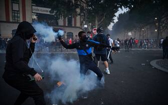 PARIS, FRANCE - AUGUST 23: A Paris Saint Germain fan throws a tear gas shell towards French Riot Police during violent confrontations between police and fans outside PSG's Parc de Princes Stadium as the Champions League Final was being played on August 23, 2020 in Paris, France. Paris Saint German football team have reached the 2019/20 UEFA Champions League finals for the first time in their history, just eleven days after celebrating their 50th Anniversary, taking on five-time winners Bayern Munich at the Estádio da Luz in Lisbon. (Photo by Kiran Ridley/Getty Images)