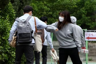 SEOUL, SOUTH KOREA - MAY 20: A teacher (R) welcomes a student back to school at Kyungbock high school on May 20, 2020 in Seoul, South Korea. Senior high school students are able to return to school from today, as South Koreans take measures to protect themselves against the spread of coronavirus (COVID-19). South Korea's education ministry announced plans to re-open schools starting for senior high school students, more than two months after schools were closed in a precautionary measure against the coronavirus. (Photo by Chung Sung-Jun/Getty Images)