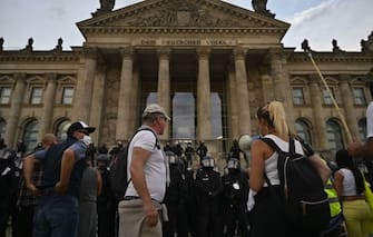 Protesters stand in front of German riot policemen who stand guard at the Reichstag building in Berlin as demonstrators tried to storm in at the end of a demonstration called by far-right and COVID-19 deniers to protest against restrictions related to the new coronavirus pandemic, in Berlin, on August 29, 2020. - At the start of August, a similar "anti-corona" march in Berlin took place with 20,000 protesters, a mixture of the hard left and right, anti-vaccination campaigners, conspiracy theorists and self-described "free thinkers". Police broke up the protest early after participants repeatedly flouted Covid-19 safety regulations. (Photo by John MACDOUGALL / AFP) (Photo by JOHN MACDOUGALL/AFP via Getty Images)