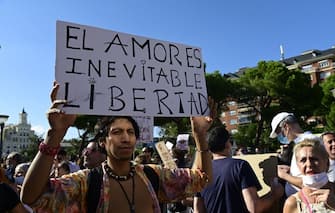 A man holds up a sign reading "Love is inevitable" during a demonstration against the mandatory use of face masks as well as other measures adopted by the Spanish government to fight against coronavirus in Spain, on August 16, 2020, at the Colon square in Madrid. - New restrictions to stop the spread of the new coronavirus, including the closure of discos and a partial ban on smoking outdoors, went into effect today in two Spanish regions as part of a raft of new measures which Spain's Health Minister Salvador Illa unveiled on August 14, 2020 to be enforced nationwide as the country battles a surge in the disease. (Photo by JAVIER SORIANO / AFP) (Photo by JAVIER SORIANO/AFP via Getty Images)