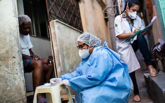 RIO DE JANEIRO, BRAZIL - SEPTEMBER 03: A Health agent of the City of Rio de Janeiro performs a COVID-19 rapid test on Aloizio dos Santos, 78, while another writes down the information of the person at Morro da Mangueira (favela) on September 3, 2020 in Rio de Janeiro, Brazil. Aloizio is part of the risk group and says that during the pandemic he had hypertension symptoms. His test result was positive. The Municipal Secreaatary of Health began the fourth stage of rapid testing for COVID-19 in Rio de Janeiro communities. According to the city of Rio de Janeiro, more than 9.000 favela residents have already been tested. The objective is to test 20.000 people, to serve as a basis for the municipality to identify the percentage of infected people inside the communities and plan the return of economic activities and services in general. (Photo by Bruna Prado/Getty Images)