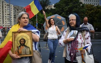A christian-orthodox believer holds an icon during a protest against the newly adopted "law of quarantine" in front of the Romanian Government headquarters in Bucharest on July 19, 2020. - After treating coronavirus patients for almost four months in the Romanian city of Timisoara (west), doctor Virgil Musta is now facing a powerful surge in the number of new daily cases, but also a string of conspiracies that are putting people's lifes in danger. (Photo by Daniel MIHAILESCU / AFP) (Photo by DANIEL MIHAILESCU/AFP via Getty Images)