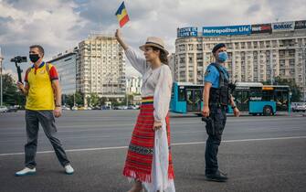 A woman waves a flag during in a protest against the Romanian government and its measures against the new coronavirus pandemic on July 12th, 2020, in Bucharest, Romania. (Photo by Andrei PUNGOVSCHI / AFP) (Photo by ANDREI PUNGOVSCHI/AFP via Getty Images)