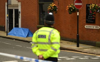 TOPSHOT - A police officer stands near to a small forensics tent as he mans a cordon at the junction of Church Street and Barwick Street, following a major stabbing incident in the centre of Birmingham, central England, on September 6, 2020. - British police declared a "major incident" early on September 6 after multiple people were stabbed in the centre of England's second city Birmingham. Violence broke out at about 12:30 am (2330 GMT Saturday) in and around the Arcadian Centre, a popular venue filled with restaurants, nightclubs and bars. (Photo by Oli SCARFF / AFP) (Photo by OLI SCARFF/AFP via Getty Images)