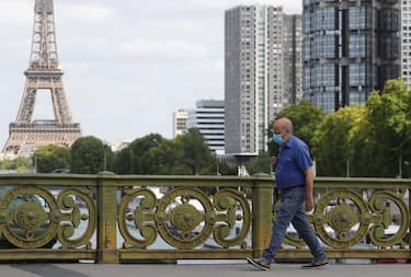 A man wears a protective face mask while walking across Pont Mirabeau bridge, near the Eiffel Tower, on August 27, 2020, in Paris. - France's prime minister on August 27 announced face masks will become compulsory throughout Paris, expressing concern over an "undeniable" trend of expanding coronavirus infection in the country. (Photo by Ludovic MARIN / AFP) (Photo by LUDOVIC MARIN/AFP via Getty Images)