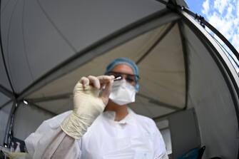 A health official shows a nasal swab sample for a Covid-19 coronavirus test in a "Covid Drive" at the University Hospital Center (CHU) in Rennes, western France, on September 7, 2020. (Photo by Damien MEYER / AFP) (Photo by DAMIEN MEYER/AFP via Getty Images)