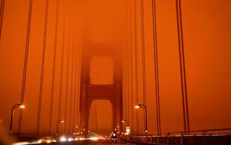 TOPSHOT - Cars drive along the San Francisco Bay Bridge under an orange smoke filled sky at midday in San Francisco, California on September 9, 2020. - More than 300,000 acres are burning across the northwestern state including 35 major wildfires, with at least five towns "substantially destroyed" and mass evacuations taking place. (Photo by Harold POSTIC / AFP) (Photo by HAROLD POSTIC/AFP via Getty Images)