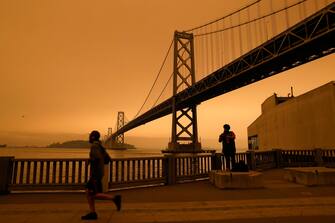 epaselect epa08657795 A view of the San Francisco Bay Bridge under an orange overcast sky in the afternoon in San Francisco, California, USA, 09 September 2020. California wildfire smoke high in the atmosphere over the San Francisco Bay Area blocked the sunlight and turned the sky a dark orange and yellow shade for most of the day.  EPA/JOHN G. MABANGLO