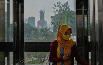 JAKARTA, INDONESIA - SEPTEMBER 14: An Indonesian woman wearing a facemark rides a glass walled elevator in the central business district September 14, 2020 in Jakarta, Indonesia. Jakarta re-entered strict social distancing measures once again after governor Anies Baswedan ordered offices, and commuter transport to restrict personnel to 50 percent capacity, as well as ordering all tourist sites in the city to close in order to curtail rising cases of the Covid-19 Coronavirus.  The continued rise in the number of cases has led to an alarming shortage of ICU and quarantine beds in hospitals COVID-19 patients.(Photo by Ed Wray/Getty Images)