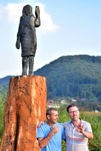 epa08671039 Unvailing of the statue from US First Lady Melania Trump by artists Bred Downey (R) and Ales 'Maxi' Zupevc (L) at her birthplace in Sevnica, Slovenia, 15 September 2020. The Old wooden statue of U.S. First Lady Melania Trump was burned on 4th July 2020.  EPA/IGOR KUPLJENIK