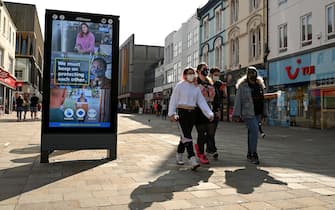 Pedestrians and shoppers, some wearing a face mask or coverings, walk past a an electronic billboard asking members of the public to follow the UK Government's guidelines to help mitigate the spread of COVID-19 in Newcastle city centre, north-east England, on September 17, 2020. - The British government on Thursday announced new restrictions for northeast England, the latest region to see a surge in coronavirus cases as Prime Minister Boris Johnson warned of a "second hump" in nationwide transmission. Residents in the northeast, which includes the cities of Newcastle and Sunderland, will no longer be allowed to socialise outside their own homes or support bubble from Friday onwards. (Photo by Oli SCARFF / AFP) (Photo by OLI SCARFF/AFP via Getty Images)