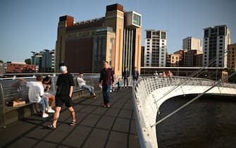 People walk across the Millennium Bridge on the River Tyne in the early evening sunshine in Newcastle upon Tyne, north-east England, on September 17, 2020. - The British government on Thursday announced new restrictions for northeast England, the latest region to see a surge in coronavirus cases as Prime Minister Boris Johnson warned of a "second hump" in nationwide transmission. Residents in the northeast, which includes the cities of Newcastle and Sunderland, will no longer be allowed to socialise outside their own homes or support bubble from Friday onwards. (Photo by Oli SCARFF / AFP) (Photo by OLI SCARFF/AFP via Getty Images)