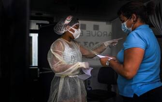 A nurse gives instructions to a woman undergoing a coronavirus test inside a bus converted into a test lab at the Sao Domingos de Rana high school in Cascais on September 14, 2020. - A coronavirus bus travelled through several schools in Cascais in the outskirts of Lisbon to deliver free COVID-19 tests to teachers and school employees days before the beginning of the academic year. (Photo by PATRICIA DE MELO MOREIRA / AFP) (Photo by PATRICIA DE MELO MOREIRA/AFP via Getty Images)