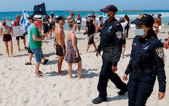 Israeli police officers patrol a beach as people demonstrate in the coastal city of Tel Aviv to protest the government's decision to close beaches during the lockdown due to the COVID-19 pandemic, on September 19, 2020. - Israel imposed a second nationwide lockdown to tackle one of the world's highest coronavirus infection rates, despite public protests over the new blow to the economy. The three-week shutdown started hours before Rosh Hashana, the Jewish New Year, and will extend through other key religious holidays, including Yom Kippur and Sukkot. (Photo by JACK GUEZ / AFP) (Photo by JACK GUEZ/AFP via Getty Images)