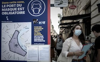 A woman wearing a protective face mask walks past a sign showing the area where wearing a protective mask is mandatory, due to the Covid-19, in Bordeaux, southwestern France, on September 16, 2020. (Photo by Philippe LOPEZ / AFP) (Photo by PHILIPPE LOPEZ/AFP via Getty Images)
