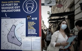 1228544806 A woman wearing a protective face mask walks past a sign showing the area where wearing a protective mask is mandatory, due to the Covid-19, in Bordeaux, southwestern France, on September 16, 2020. (Photo by Philippe LOPEZ / AFP) (Photo by PHILIPPE LOPEZ/AFP via Getty Images)