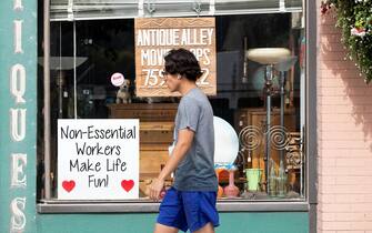 NEW WESTMINSTER, BRITISH COLUMBIA - SEPTEMBER 06: A man walks past a sign that reads, "Non-Essential Workers Make Life Fun" on September 06, 2020 in New Westminster, British Columbia, Canada.  The Government of British Columbia has extended the Provincial State of Emergency until September 15, 2020 under the Emergency Program Act to support the Province's COVID-19 pandemic response. (Photo by Andrew Chin/Getty Images)