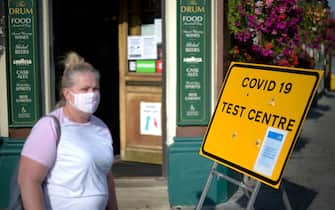 Pedestrians wearing facemasks walks past a sign for a Covid-19 test centre in Leyton, east London on September 19, 2020. (Photo by DANIEL LEAL-OLIVAS / AFP) (Photo by DANIEL LEAL-OLIVAS/AFP via Getty Images)