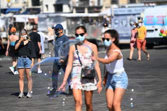 A girl wearing face mask take a picture with mobile phone in the old harbour of Marseille, southestern France, on August 26, 2020. - The southern port city of Marseille became the latest to make face coverings compulsory city-wide outdoors, while bars and restaurants will close every day at 11 pm. (Photo by Christophe SIMON / AFP) (Photo by CHRISTOPHE SIMON/AFP via Getty Images)