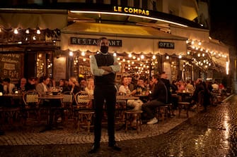 PARIS, FRANCE - SEPTEMBER 23: A waiter stands outside a busy terrace as Parisians relax as the French Government announced that from Monday all bars and cafes in Paris will be made to shut at 10pm as part of a string of new measures to curb the spread of Covid-19 in France on September 23, 2020 in Paris, France. With the rise in Coronavirus cases in France at 204 per 100,000 inhabitants, the French Government have followed other governments in introducing new restrictions aimed at reducing the spread of Covid-19 whilst avoiding another national lockdown. In large cities, including Paris, gatherings will be limited to ten people in public spaces, bars to close at 10 p.m., local and student parties will be prohibited. (Photo by Kiran Ridley/Getty Images)