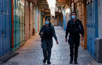 Israeli policemen wearing protective masks due to the COVID-19 pandemic, monitor a street lined with closed shops in Jerusalem's old city, on September 19, 2020, amid lockdown due to a spike in infection cases. - Israel imposed a second nationwide lockdown to tackle one of the world's highest coronavirus infection rates, despite public protests over the new blow to the economy. The three-week shutdown from yesterday just hours before Rosh Hashana, the Jewish New Year, and will extend through other key religious holidays, including Yom Kippur and Sukkot. (Photo by MENAHEM KAHANA / AFP) (Photo by MENAHEM KAHANA/AFP via Getty Images)