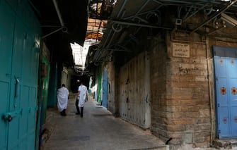 Ultra-Orthodox Jews wearing protective masks due to the COVID-19 pandemic, walk on an empty street lined with closed shops on their way to the synagogue for the Rosh Hashana (Jewish New Year) prayers in Jerusalem's old city, on September 19, 2020, amid lockdown due to a spike in infection cases. - Israel imposed a second nationwide lockdown to tackle one of the world's highest coronavirus infection rates, despite public protests over the new blow to the economy. The three-week shutdown from yesterday just hours before Rosh Hashana, the Jewish New Year, and will extend through other key religious holidays, including Yom Kippur and Sukkot. (Photo by MENAHEM KAHANA / AFP) (Photo by MENAHEM KAHANA/AFP via Getty Images)