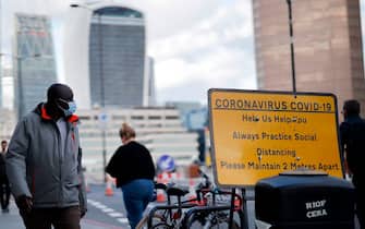 A pedestrian wears a facemask due to the novel coronavirus COVID-19 pandemic on London Bridge in central London on September 25, 2020. - Britain's Prime Minister Boris Johnson, this week announced a host of new restrictions, including early closing times for pubs and again asking people to work from home if possible, as COVID-19 cases spike. (Photo by Tolga Akmen / AFP) (Photo by TOLGA AKMEN/AFP via Getty Images)
