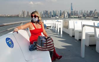 NEW YORK, NEW YORK - SEPTEMBER 25:  A passenger wearing a protective mask sits on the deck of a NY Waterway ferry as the city continues Phase 4 of reopening following restrictions imposed to slow the spread of coronavirus on September 25, 2020 in New York City. NY Waterway recently restored commuter ferry service from Port Imperial in Weehawken, NJ to their two Lower Manhattan terminals, Brookfield Place/Battery Park City and Pier 11/Wall Street, as well as service from 14th Street in Hoboken, NJ and the Hoboken/NJ TRANSIT terminal to Lower Manhattan. (Photo by Cindy Ord/Getty Images)