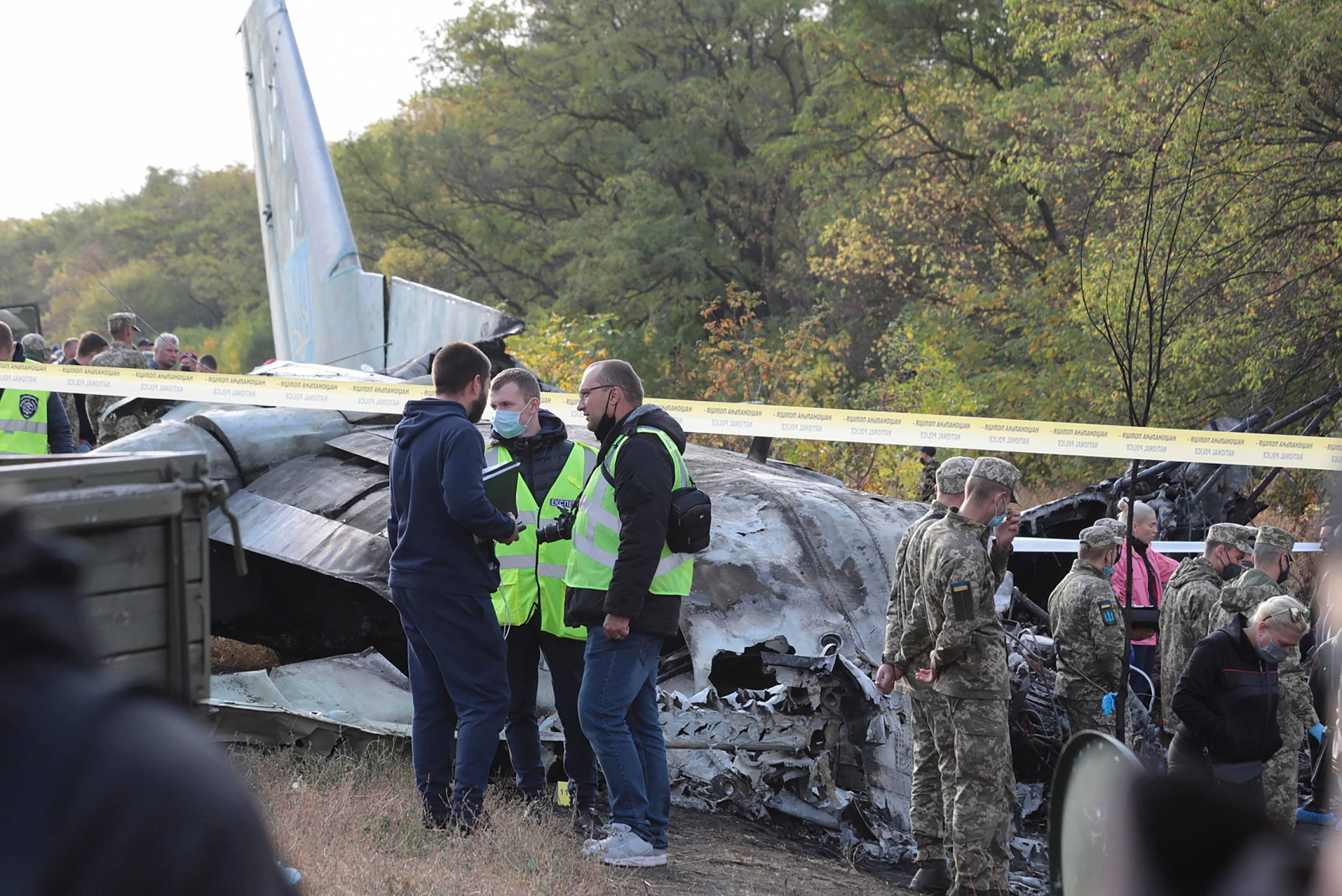 epa08698267 Rescuers inspect the crash site of the An-26 plane near of Chuguev city of Kharkiv's area, Ukraine, 26 September 2020. The An-26 plane of the Ukrainian Air Force crashed while landing at the Chuguev airport in Kharkiv region. Asides from the crew, 21 cadets of the Kharkiv National University of the Air Force were on board because it was a training flight according to preliminary information. A fire broke out during the plane crash. 22 people were killed, two were injured. A total of 28 persons were on board as local media report.  EPA/SERGEY KHRUPOV