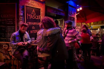 PARIS, FRANCE - SEPTEMBER 28: People embrace outside at a bar before curfew starts forcing bars and cafes in the capital to close early at 10pm on September 28, 2020 in Paris, France. The French capital has seen a surge in Covid-19 cases and was recently designated a "red zone," which imposes set of restrictions on public gatherings and the sale of alcohol. From today bars are required to remain closed between 10PM and 6AM. (Photo by Kiran Ridley/Getty Images)