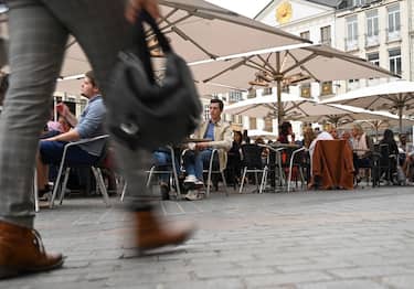 A woman walks by as clients sit at a cafe's terrace on September 9, 2020 in Lille, northern France. - From this Monday evening and for a fortnight, restaurants, night grocery stores, and bars will close at 12:30 a.m. every day in Lille to prevent the spread of the covid-19 pandemic caused  by the novel coronavirus. (Photo by DENIS CHARLET / AFP) (Photo by DENIS CHARLET/AFP via Getty Images)
