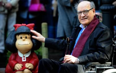 Cartoonist Joaquin Salvador Lavado, aka Quino, poses beside a sculpture of his creature Mafalda at the San Francisco park in Oviedo on October 23, 2014 on the eve of the Prince of Asturias awards ceremony. Quino has been awarded the 2014 Prince of Asturias Award for Communication and Humanities. AFP PHOTO/ MIGUEL RIOPA (Photo by Miguel RIOPA / AFP) (Photo by MIGUEL RIOPA/AFP via Getty Images)