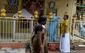 A health worker (C) wearing personal protective equipment (PPE) collects a swab sample from a man for a Covid-19 coronavirus test as people walk past at a temporarory collection centre at a Hindu temple in Hyderabad on September 30, 2020. (Photo by NOAH SEELAM / AFP) (Photo by NOAH SEELAM/AFP via Getty Images)
