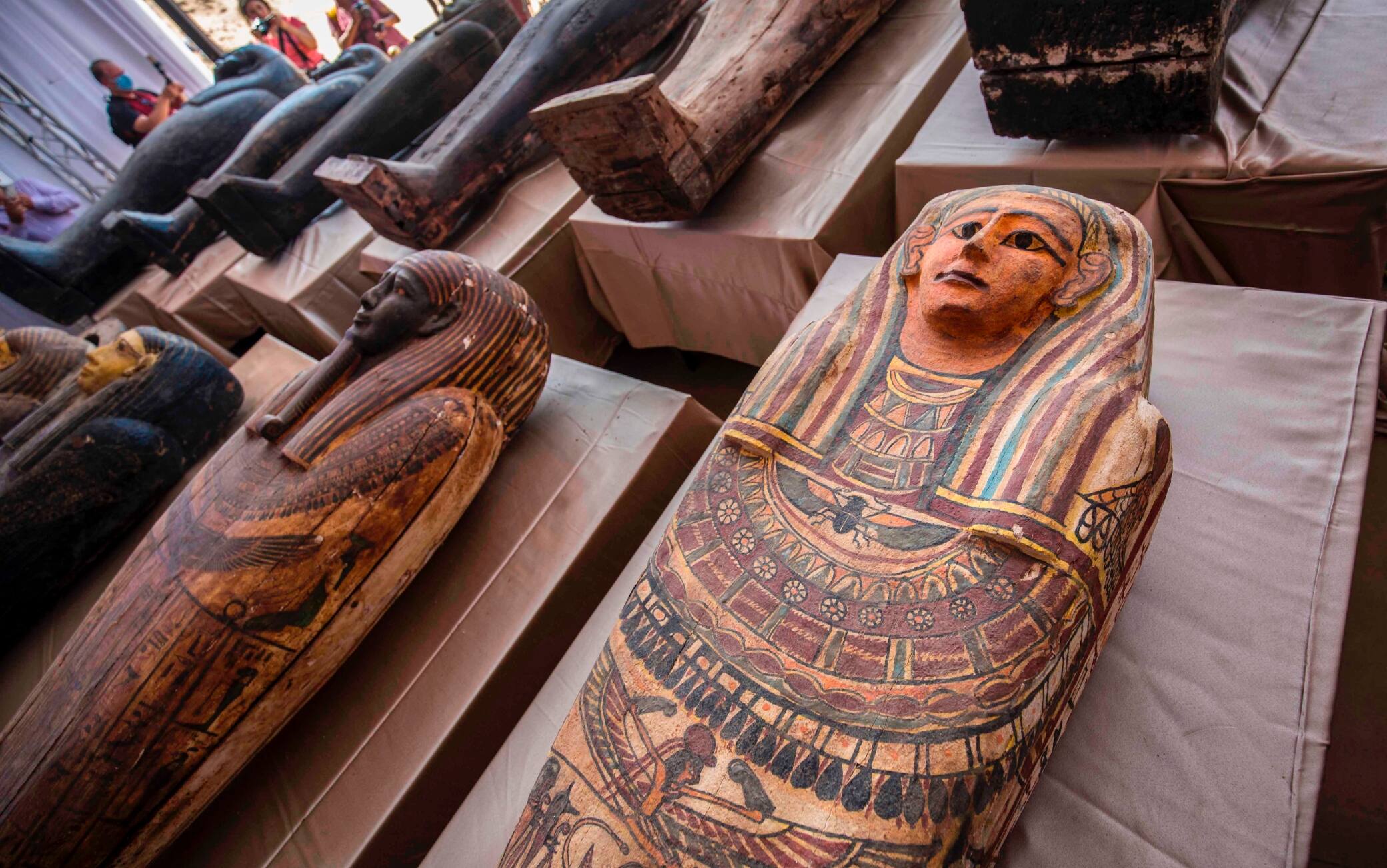 A picture taken on October 3, 2020 shows sarcophaguses, excavated by the Egyptian archaeological mission which discovered a deep burial well with more than 59 human coffins closed for more than 2,500 years, displayed during a press conference  at the Saqqara necropolis, 30 kms south of the Egyptian capital Cairo. - They were unearthed south of Cairo in the sprawling burial ground of Saqqara, the necropolis of the ancient Egyptian capital of Memphis, a UNESCO World Heritage site. Their exteriors are covered in intricate designs in vibrant colours as well as hieroglyphic pictorials. (Photo by Khaled DESOUKI / AFP) (Photo by KHALED DESOUKI/AFP via Getty Images)
