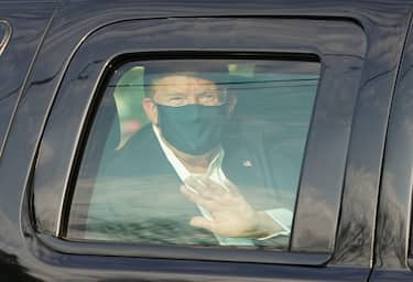 US President Trump waves from the back of a car in a motorcade outside of Walter Reed Medical Center in Bethesda, Maryland on Ocotber 4, 2020. (Photo by ALEX EDELMAN / AFP)