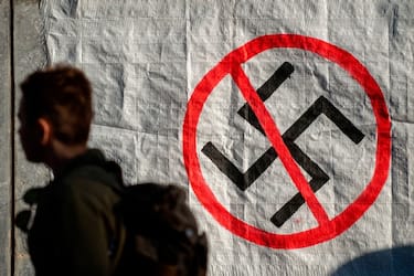 A man walks next to a logo of Nazi swastika during an anti-fascist rally outside the Court of Appeal during the testify of former MP and leader of Golden Dawn party Nikolaos Michaloliakos, on November 6, 2019, in Athens. - The 61-year-old Holocaust denier is one of nearly 70 defendants facing sentences of five to 20 years in prison. The main charge against them is participation in a criminal organisation, in addition to a host of other indictments related to murder and assault. (Photo by Angelos Tzortzinis / AFP) (Photo by ANGELOS TZORTZINIS/AFP via Getty Images)