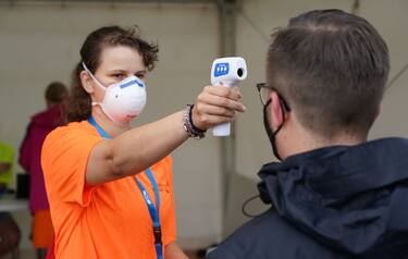 LEIPZIG, GERMANY - AUGUST 22: A worker checks the temperature of a participant registering for the RESTART-19 Covid transmission risk assessment study at an indoor arena during the coronavirus pandemic on August 22, 2020 in Leipzig, Germany. The study, organized by the University Hospital of Halle (Saale), simulates a live concert venue with several thousand audience members in three different scenarios in order to develop risk reduction measures for large events. All participants had to undergo a Covid-19 test within the last 48 hours and test negative in order to take part.  (Photo by Sean Gallup/Getty Images)