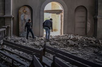 Two men walk through the rubble and debris on October 8, 2020 inside the damaged Ghazanchetsots (Holy Saviour) Cathedral in the historic city of Shusha, some 15 kilometers from the disputed Nagorno-Karabakh province's capital Stepanakert, that was hit by a bomb as fighting between Armenian and Azerbaijani forces spilled over today ahead of a first meeting of international mediators in Geneva. - Nagorno-Karabakh broke away from Azerbaijan in a 1990s war that claimed the lives of some 30,000 people. The Armenian separatists declared independence, but no countries recognise its autonomy and it is still acknowledged by world leaders as part of Azerbaijan. (Photo by ARIS MESSINIS / AFP) (Photo by ARIS MESSINIS/AFP via Getty Images)