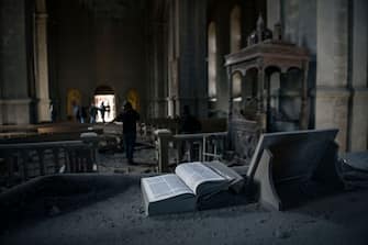 TOPSHOT - A Bible lies open on an altar as journalists report on October 8, 2020 inside the damaged Ghazanchetsots (Holy Saviour) Cathedral in the historic city of Shusha, some 15 kilometers from the disputed Nagorno-Karabakh province's capital Stepanakert, that was hit by a bomb as fighting between Armenian and Azerbaijani forces spilled over today ahead of a first meeting of international mediators in Geneva. - Nagorno-Karabakh broke away from Azerbaijan in a 1990s war that claimed the lives of some 30,000 people. The Armenian separatists declared independence, but no countries recognise its autonomy and it is still acknowledged by world leaders as part of Azerbaijan. (Photo by ARIS MESSINIS / AFP) (Photo by ARIS MESSINIS/AFP via Getty Images)