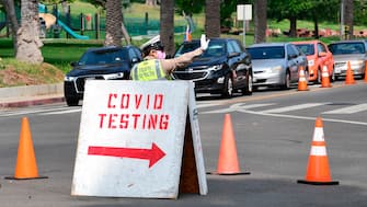 A traffic warden directs traffic as motorists arrive for Covid-19 tests at Dodger Stadium in Los Angeles, California on October 8, 2020. - Health officials are closely monitoring coronavirus case numbers this week after LA County saw a one-day spike, the highest since mid-August, which could threaten the ability to reopen more businesses. (Photo by Frederic J. BROWN / AFP) (Photo by FREDERIC J. BROWN/AFP via Getty Images)