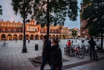 KRAKOW, POLAND - OCTOBER 07: People wear protective face masks as they walk on Krakow's UNESCO listed Main Square on October 07, 2020 in Krakow, Poland. The  Central-Eastern European country has been dealing with a second wave of COVID -19 and today recorded its highest daily figures for both new coronavirus cases (3,003) and deaths (75). Due to the recent pick of Coronavirus cases, the government adopted a â  zone policyâ   where mandatory protective face mask and other measures will apply on the yellow and red zones. The country reported over 2500 deaths related to Covid-19 and more than 100,000 infections. (Photo by Omar Marques/Getty Images)