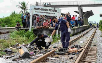 Investigators examine wreckage on the tracks next to an overturned bus involved in a deadly collision with a train by Khlong Kwaeng Klan railway station in Chachoengsao province, east of the Thai capital Bangkok, on October 11, 2020. (Photo by Mladen ANTONOV / AFP) (Photo by MLADEN ANTONOV/AFP via Getty Images)