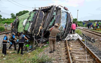 Investigators work by the wreckage of an overturned bus involved in a deadly collision with a train next to Khlong Kwaeng Klan railway station in Chachoengsao province, east of the Thai capital Bangkok, on October 11, 2020. (Photo by Mladen ANTONOV / AFP) (Photo by MLADEN ANTONOV/AFP via Getty Images)