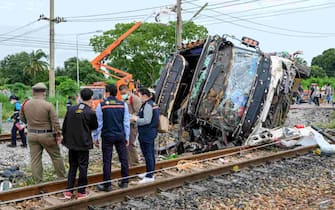 Investigators work by the wreckage of an overturned bus involved in a deadly collision with a train next to Khlong Kwaeng Klan railway station in Chachoengsao province, east of the Thai capital Bangkok, on October 11, 2020. (Photo by Mladen ANTONOV / AFP) (Photo by MLADEN ANTONOV/AFP via Getty Images)