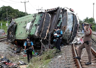 epa08735136 Thai police and forensic officers inspect a wreckage bus after it collided with a train at Khlong Kwaeng Klan railway station in Chachoengsao province, Thailand, 11 October 2020. Twenty people were killed while another 30 injured after a train crashed into a bus carrying Buddhist devotees heading to a temple for a merit making ceremony to mark the end of Buddhist Lent, police said.  EPA/RUNGROJ YONGRIT