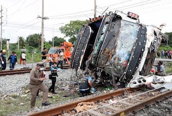 epa08735141 Thai policemen and forensic officers inspect a wreckage bus after it collided with a train at Khlong Kwaeng Klan railway station in Chachoengsao province, Thailand, 11 October 2020. Twenty people were killed while another 30 injured after a train crashed into a bus carrying Buddhist devotees heading to a temple for a merit making ceremony to mark the end of Buddhist Lent, police said.  EPA/RUNGROJ YONGRIT
