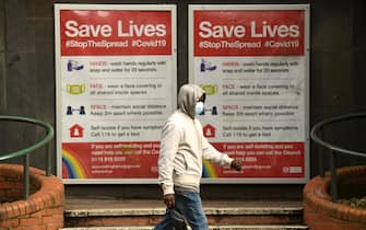 A man wearing a protective face mask passes a board displaying information how to restrict the spread of coronavirus covid-19, in central Nottingham in central England on October 9, 2020. - Pubs and restaurants in coronavirus hotspots look set to face fresh restrictions after Downing Street said new data suggests there is "significant" transmission taking place in hospitality settings. A "range of measures" is being looked at, with a particular focus on northern England, where it says infection rates are rising fastest. (Photo by Oli SCARFF / AFP) (Photo by OLI SCARFF/AFP via Getty Images)