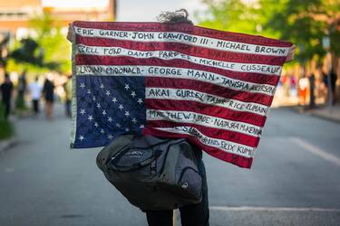 TOPSHOT - A protester holds up an upside down US flag with names of victims during a demonstration against racism and police brutality in Pittsburgh, Pennsylvania, on June 6, 2020. - Demonstrations are being held across the US following the death of George Floyd on May 25, 2020, while being arrested in Minneapolis, Minnesota. (Photo by Maranie R. STAAB / AFP) (Photo by MARANIE R. STAAB/AFP via Getty Images)